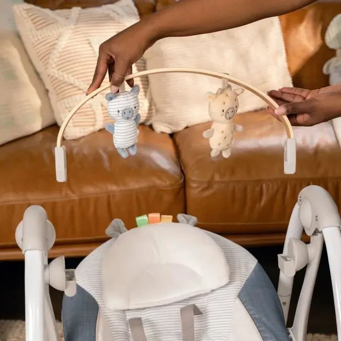 Ingenuity Balancelle bébé électrique pliable Swing 'n Go - Chambray, 5 vitesses, 8 mélodies, avec arc d'activités amovible