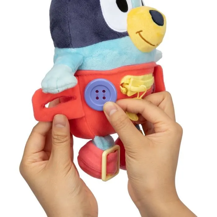 Bluey Peluche d'éveil et d'activités Bébé avec fermetures à lacets, boutons et zip pour apprendre l'habillement et la motricité fine - 25 cm