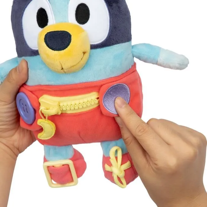Bluey Peluche d'éveil et d'activités Bébé avec fermetures à lacets, boutons et zip pour apprendre l'habillement et la motricité fine - 25 cm