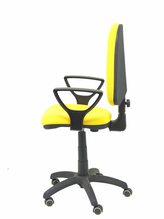Chaise de bureau Aýna avec mécanisme Contact permanent de base, revêtue de tissu jaune. Équipée d'une base en polyamide noir, d'accoudoirs fixes et de roulettes pour parquet