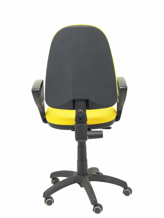 Chaise de bureau Aýna avec mécanisme Contact permanent de base, revêtue de tissu jaune. Équipée d'une base en polyamide noir, d'accoudoirs fixes et de roulettes pour parquet