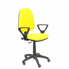 Chaise de bureau Aýna avec mécanisme Contact permanent de base, revêtue de tissu jaune. Équipée d'une base en polyamide noir, d'accoudoirs fixes et de roulettes pour parquet